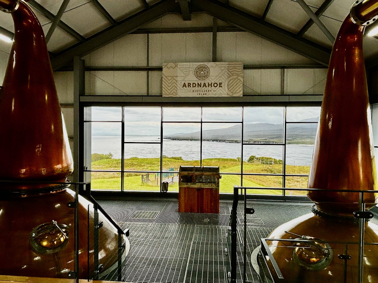 アードナホー蒸溜所のポットスティルの間からジュラ島を望む